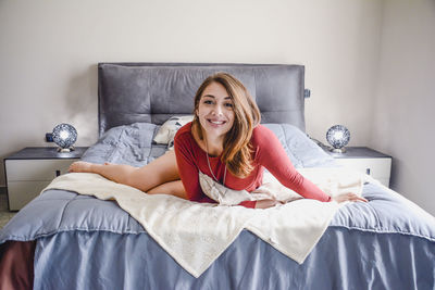 Portrait of smiling young woman lying on bed