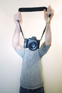 Midsection of woman holding camera against wall