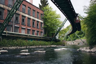 Bridge over river by buildings against sky