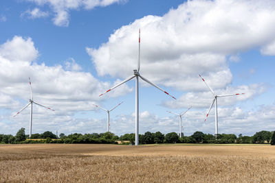 Windmills on field against sky