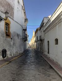 Road amidst buildings against clear sky