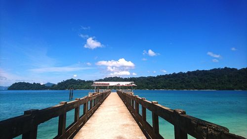 Pier over sea against blue sky