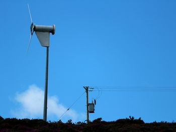 Low angle view of electricity pylon on field against clear blue sky