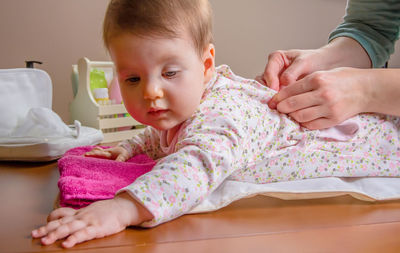 Woman undressing baby girl at home