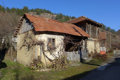 Old house on field by buildings against sky