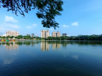 Buildings by lake against blue sky