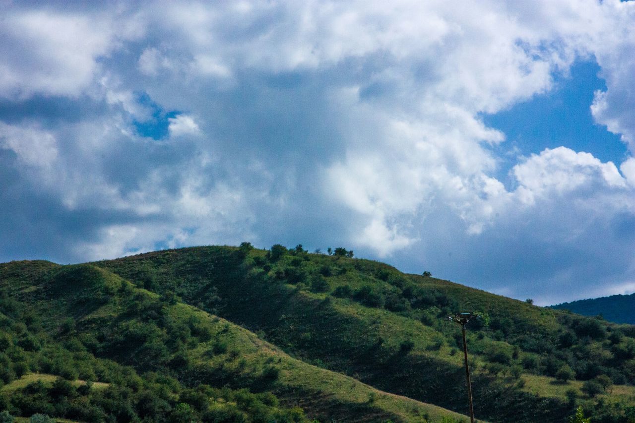 mountain, sky, tranquil scene, tranquility, scenics, beauty in nature, cloud - sky, landscape, nature, green color, cloudy, tree, cloud, mountain range, non-urban scene, idyllic, day, remote, hill, lush foliage