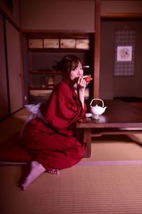 Woman looking away while sitting on table at home