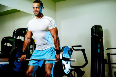 Smiling man lifting dumbbells in gym