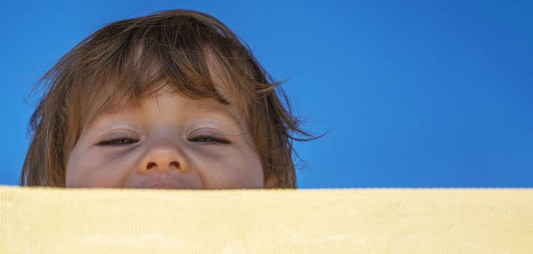 Close-up portrait of cute girl baby against blue wall