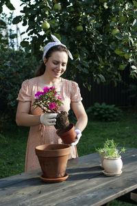 Woman holding flower pot on potted plant