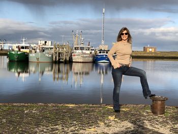 Portrait of woman standing on pier by sea