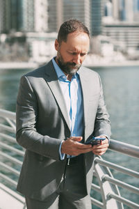 Mid adult man using mobile phone while standing outdoors