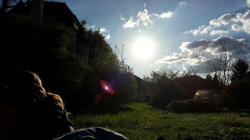 Rear view of woman by house against sky during sunset