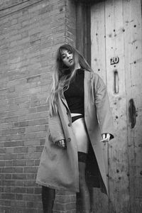 Portrait of woman standing against brick wall