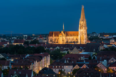 Illuminated buildings in city against clear blue sky