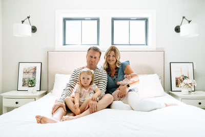 Portrait of a family sitting together on a bed making silly faces