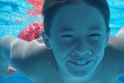 Close-up portrait of smiling boy swimming in pool