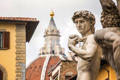 Low angle view of statue and church at piazza della signoria