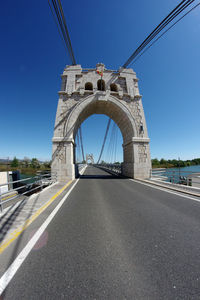 Low angle view of bridge over road against sky