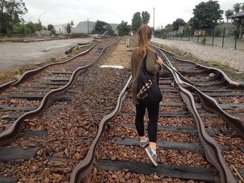 Rear view of woman on railroad tracks against sky