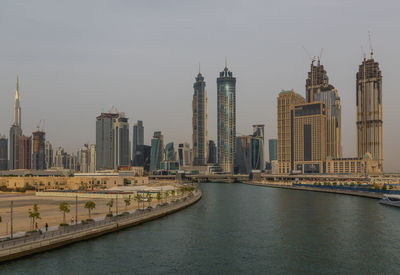View of buildings by river against sky in city