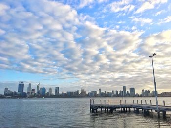 City at waterfront against cloudy sky