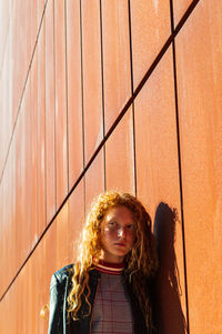 Portrait of a young woman standing against wall