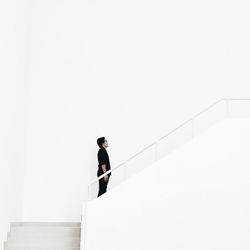 Man standing on staircase against white wall in building