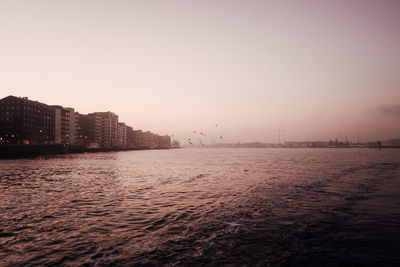 Scenic view of sea against buildings during sunset