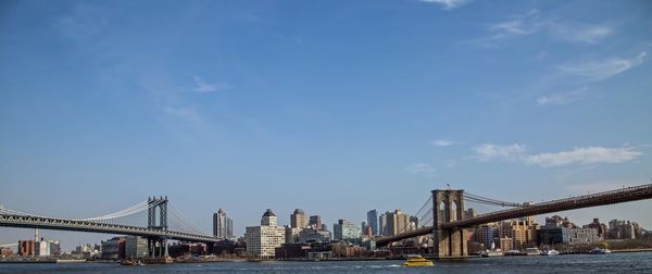 Suspension bridges in city against sky