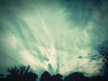 Low angle view of trees against cloudy sky