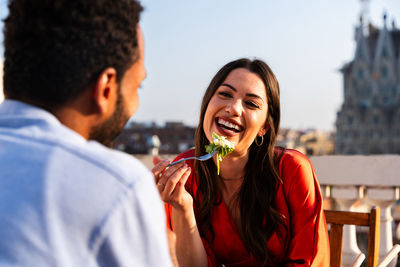 Side view of young woman blowing bubbles while standing outdoors