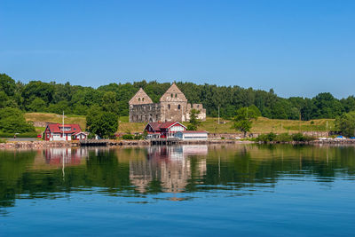 Scenic view of lake by building against clear blue sky