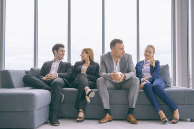 Business people talking while sitting on sofa in office