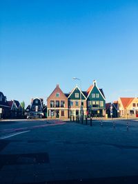 Buildings by street against blue sky