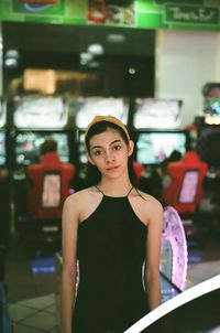 Portrait of young woman standing against illuminated wall