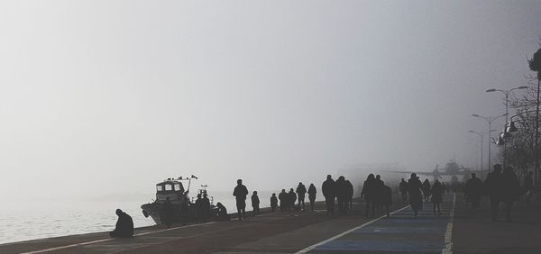 Silhouette of people walking against clear sky