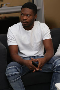 Young man using mobile phone while sitting on sofa at home