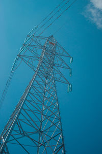 Low angle view of electricity pylon against blue sky