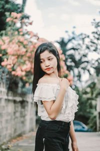 Portrait of beautiful young woman standing against trees