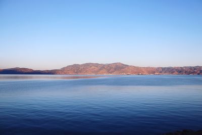 Scenic view of lake against clear blue sky