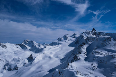 Scenic view of snowcapped mountains against blue sky