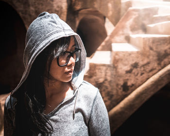 Mid adult woman looking away while standing against built structure