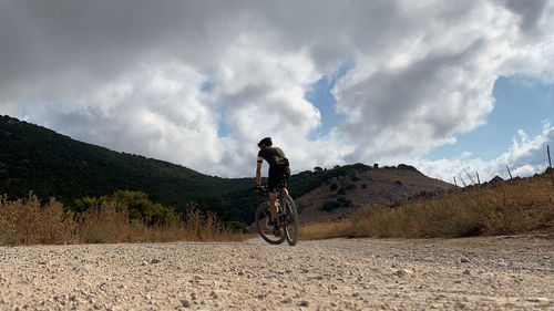 Man riding bicycle on road against sky