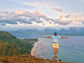 Rear view of man looking at sea against sky