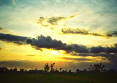 Scenic view of dramatic sky over field during sunset