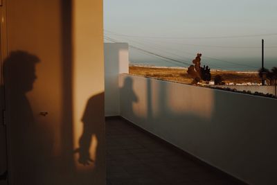 People standing by swimming pool against sky during sunset