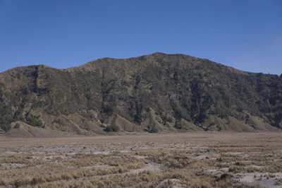 Scenic view of arid landscape against clear blue sky