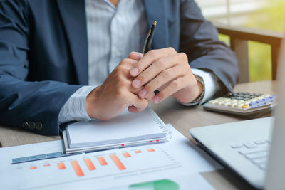 Midsection of businessman sitting at desk in office